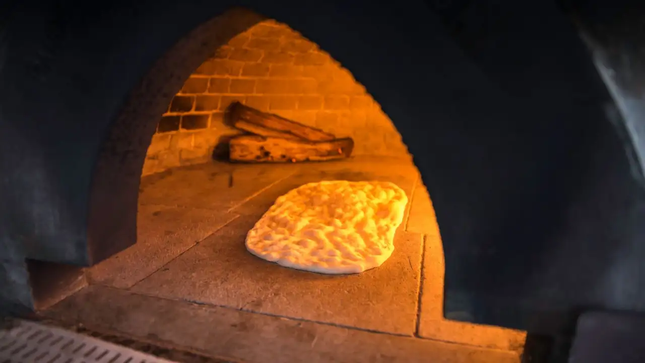 cooking a flatbread in a heated brick pizza oven
